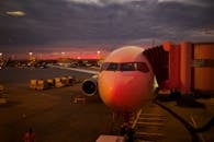 Plane boarding at sunset with vibrant sky colors and airport lights.